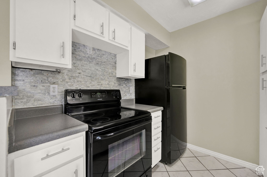 Kitchen with backsplash, white cabinetry, light tile flooring, and black appliances