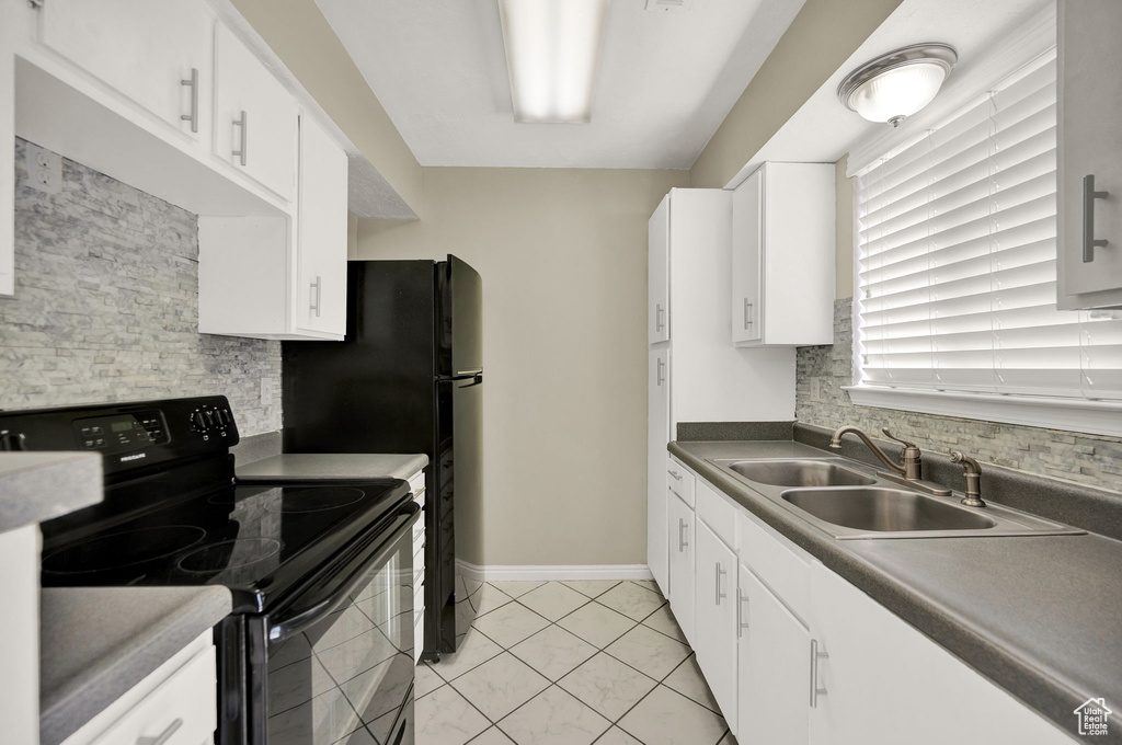 Kitchen with white cabinets, sink, light tile floors, and electric range