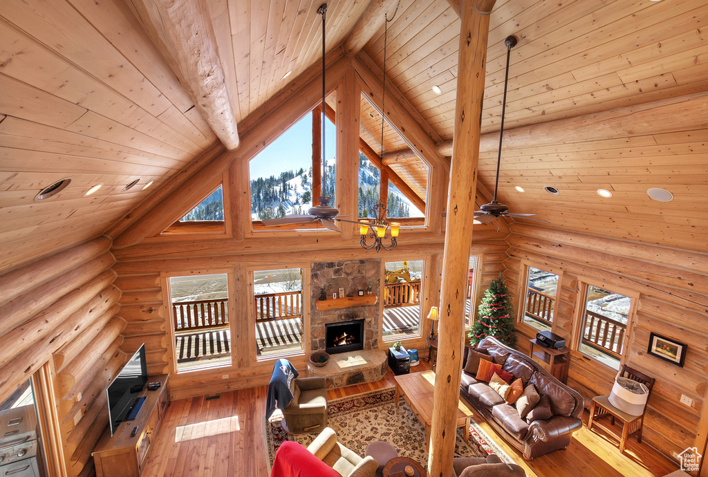 Living room with high vaulted ceiling, rustic walls, beamed ceiling, and hardwood / wood-style floors