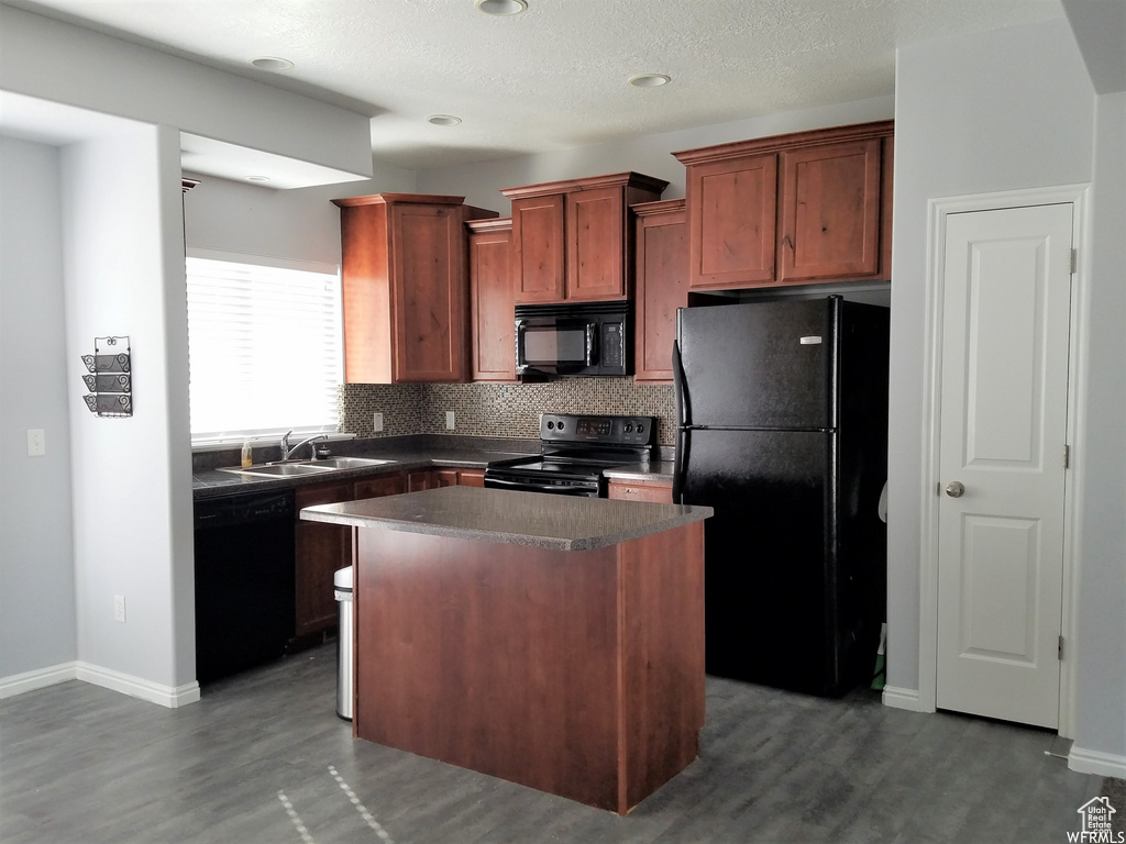 Kitchen with black appliances, tasteful backsplash, sink, dark hardwood / wood-style flooring, and a center island