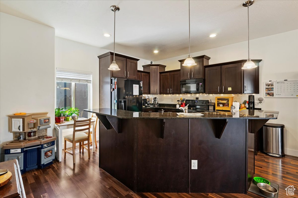 Kitchen featuring decorative light fixtures, black appliances, and dark hardwood / wood-style flooring