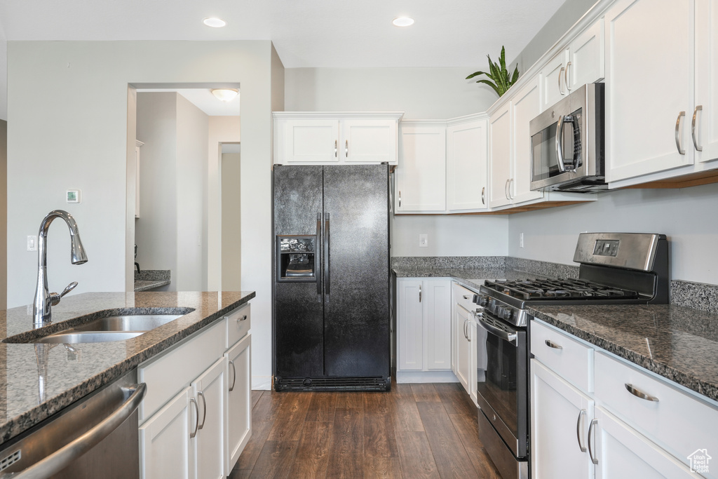Kitchen with white cabinets, sink, appliances with stainless steel finishes, and dark wood-type flooring