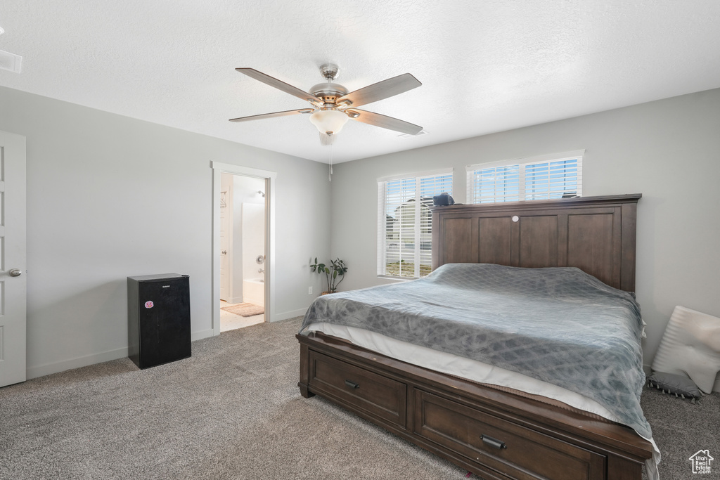 Carpeted bedroom featuring ceiling fan and connected bathroom