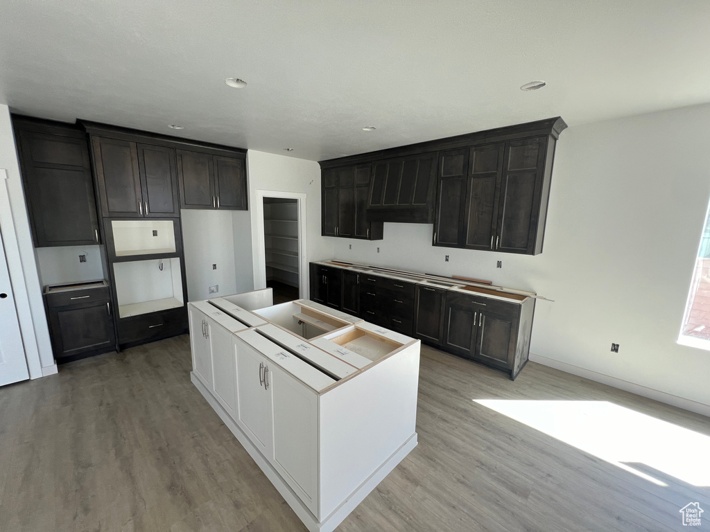 Kitchen featuring dark brown cabinets, light hardwood / wood-style floors, a center island, and custom exhaust hood