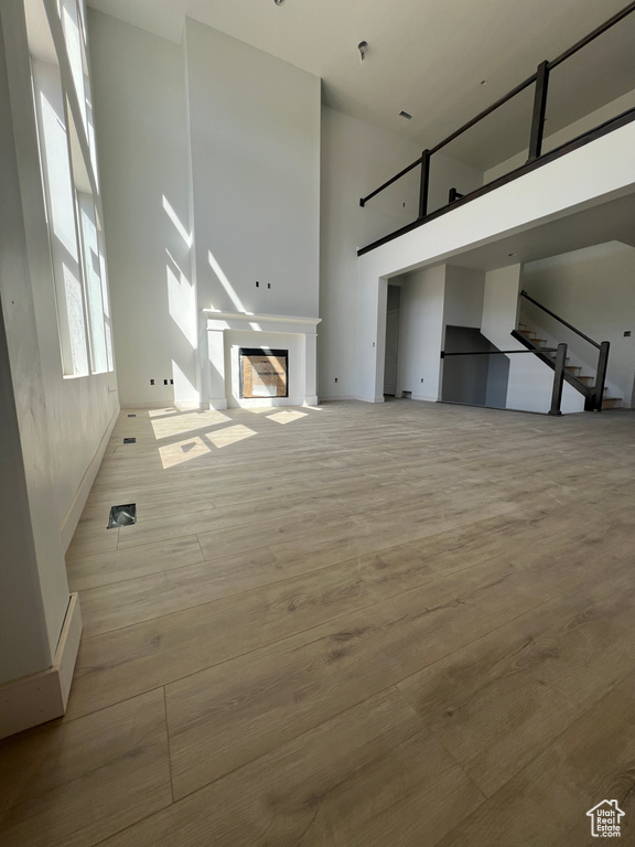 Unfurnished living room with light hardwood / wood-style flooring and a high ceiling