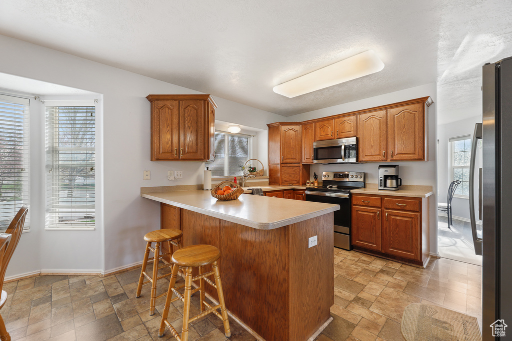 Kitchen featuring plenty of natural light, stainless steel appliances, light tile flooring, and a breakfast bar