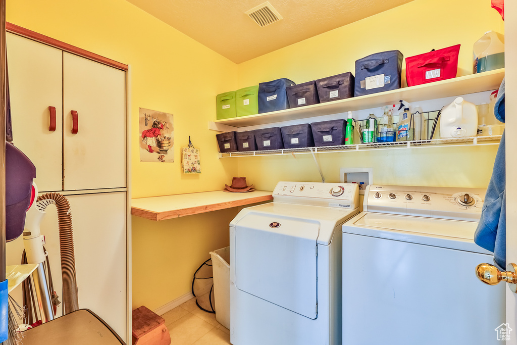 Laundry room featuring light tile flooring and washer and clothes dryer