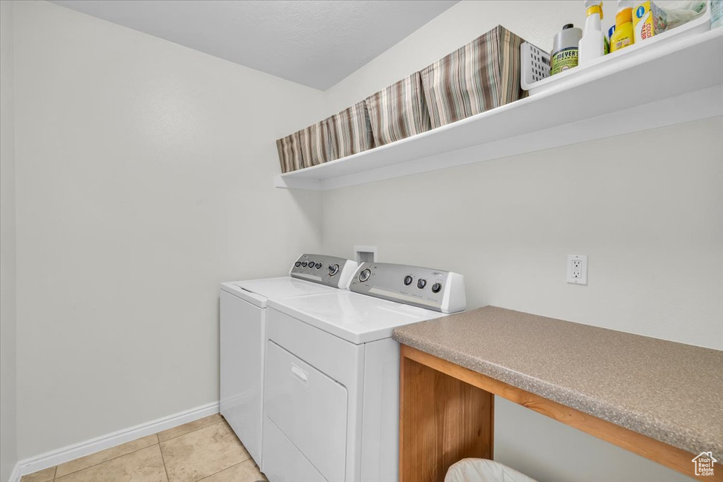Washroom with washing machine and clothes dryer and light tile floors