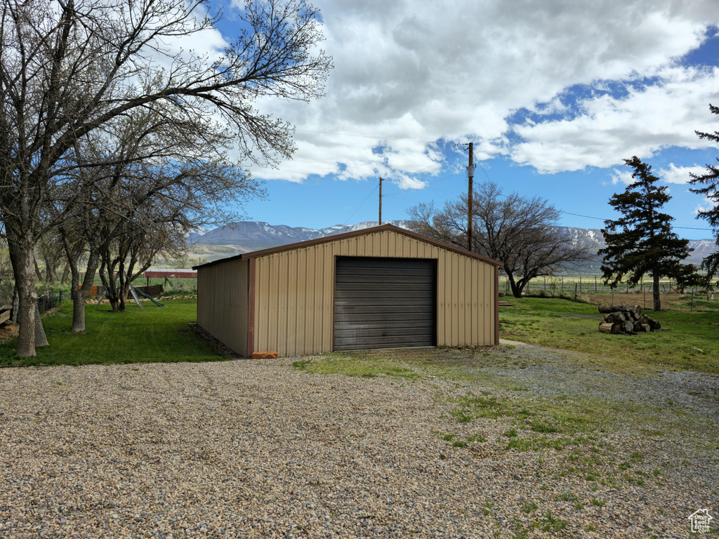 View of shed / structure featuring a garage, a mountain view, and a yard