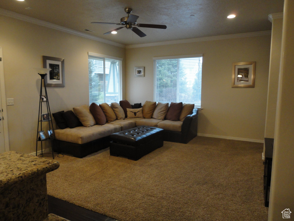 Living room featuring ceiling fan, dark carpet, and a wealth of natural light