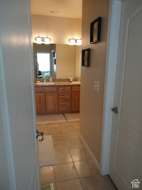 Bathroom with dual sinks, oversized vanity, and tile floors