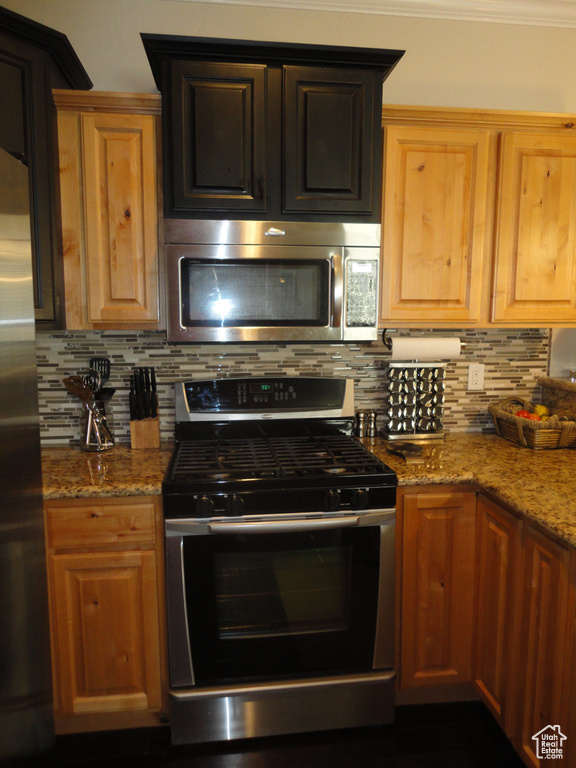 Kitchen with tasteful backsplash, appliances with stainless steel finishes, and light stone countertops