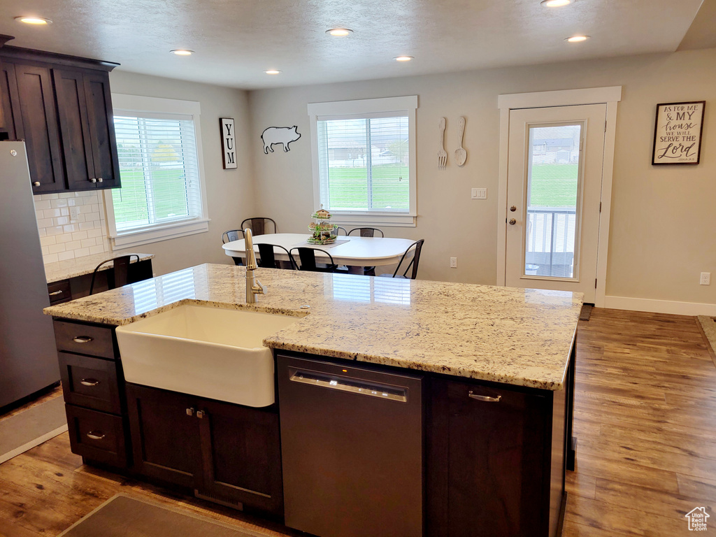 Kitchen featuring appliances with stainless steel finishes, hardwood / wood-style floors, an island with sink, and a healthy amount of sunlight