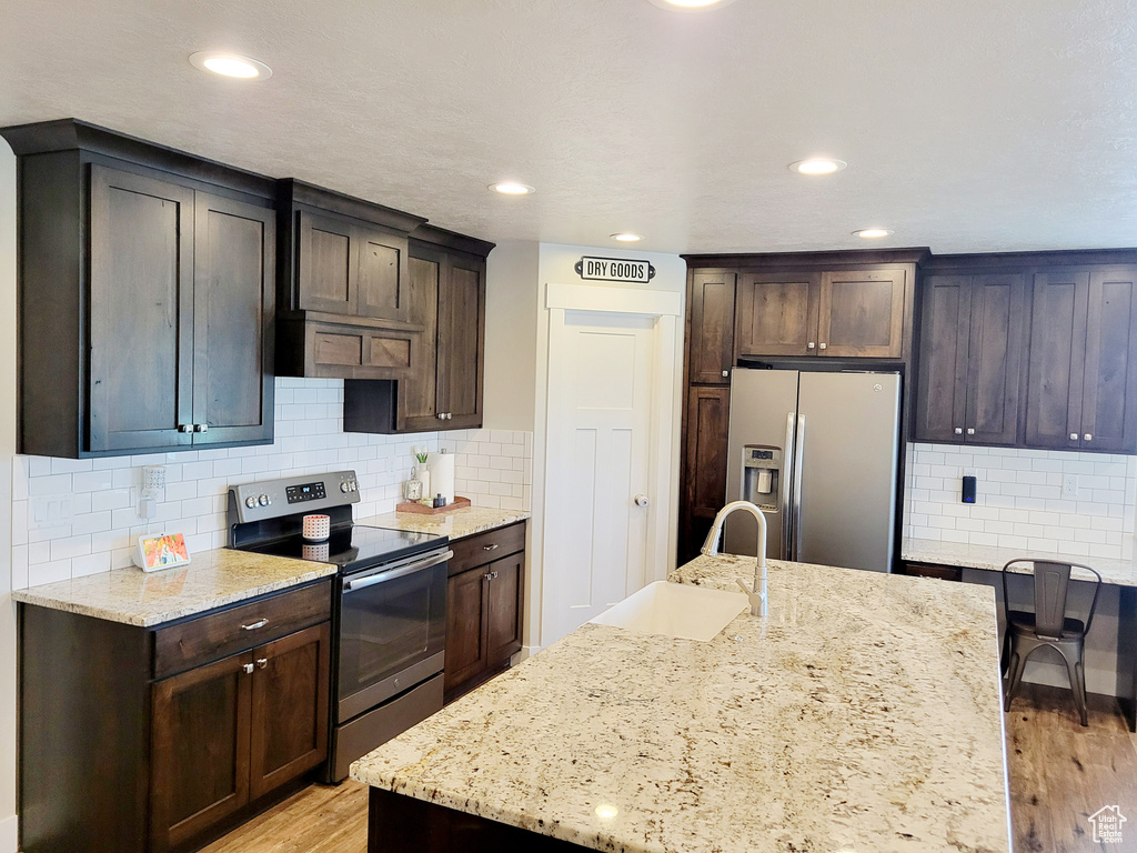 Kitchen with sink, light hardwood / wood-style flooring, tasteful backsplash, and stainless steel appliances
