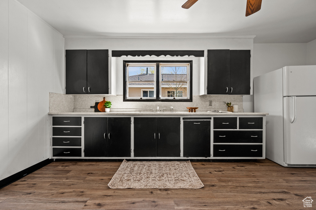 Kitchen featuring backsplash, ceiling fan, sink, dark hardwood / wood-style flooring, and white refrigerator