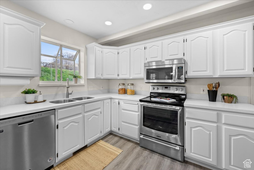 Kitchen featuring sink, appliances with stainless steel finishes, light hardwood / wood-style floors, and white cabinetry