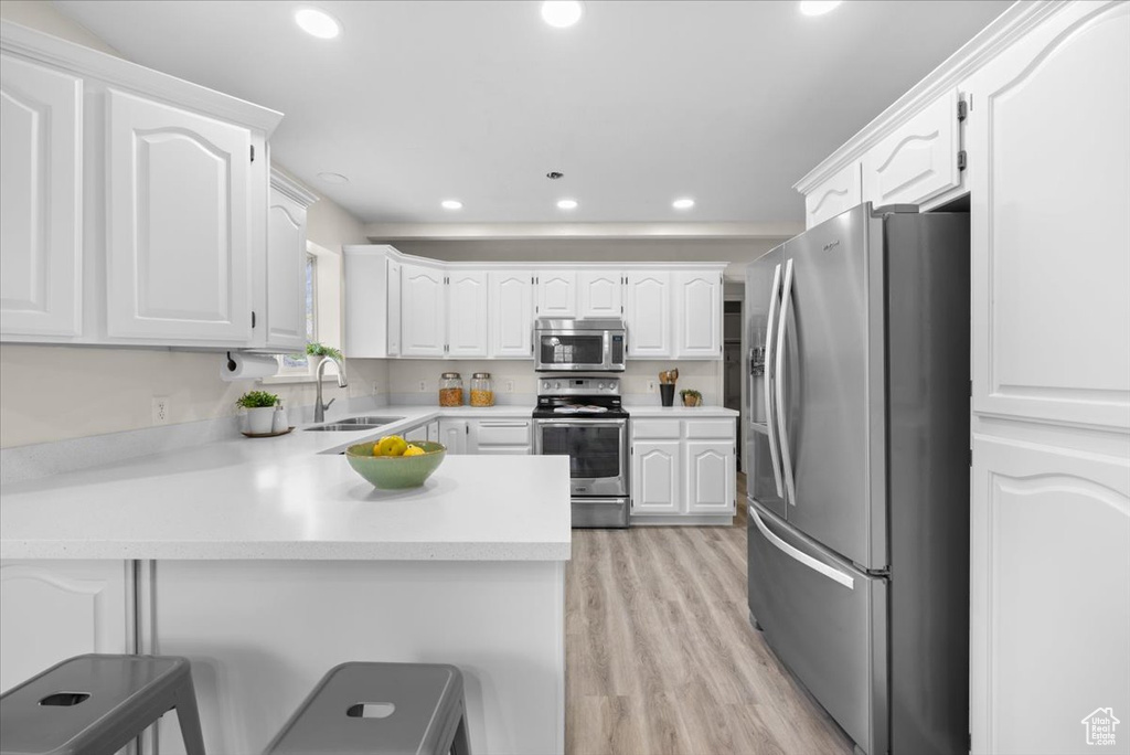 Kitchen featuring stainless steel appliances, white cabinetry, sink, and light wood-type flooring