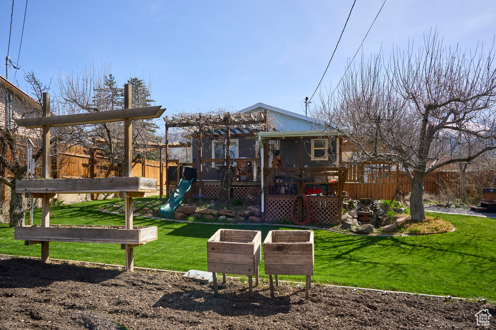 Back of property with a deck, a yard, and a playground