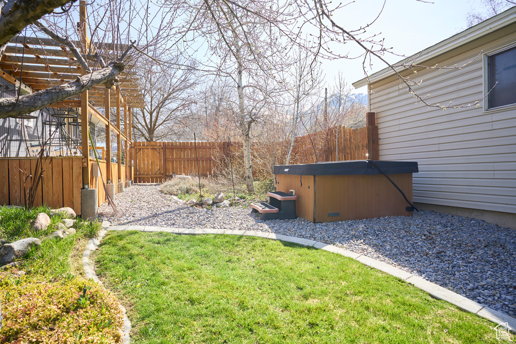 View of yard with a hot tub and a pergola