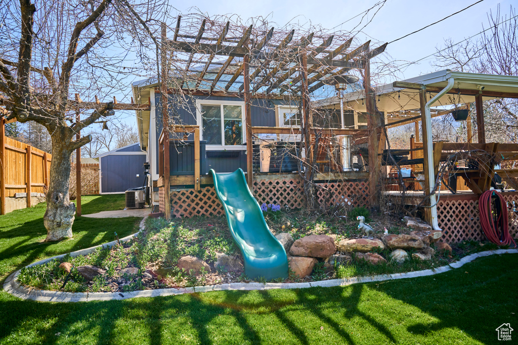 View of play area featuring a yard, a deck, and a pergola