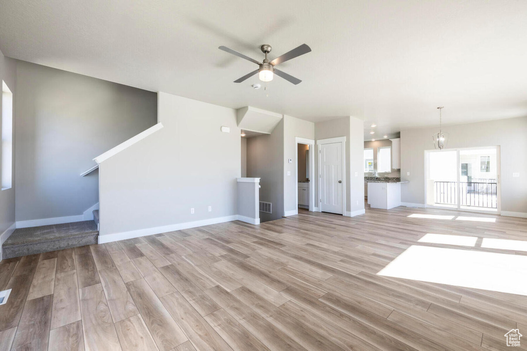 Unfurnished living room featuring ceiling fan and light hardwood / wood-style flooring