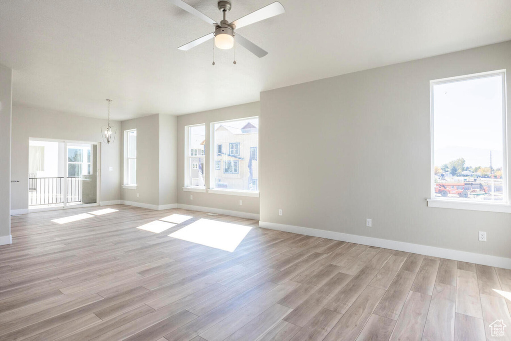 Empty room with ceiling fan, light wood-type flooring, and a wealth of natural light