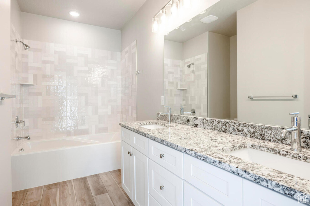 Bathroom with tiled shower / bath combo, hardwood / wood-style floors, and dual bowl vanity
