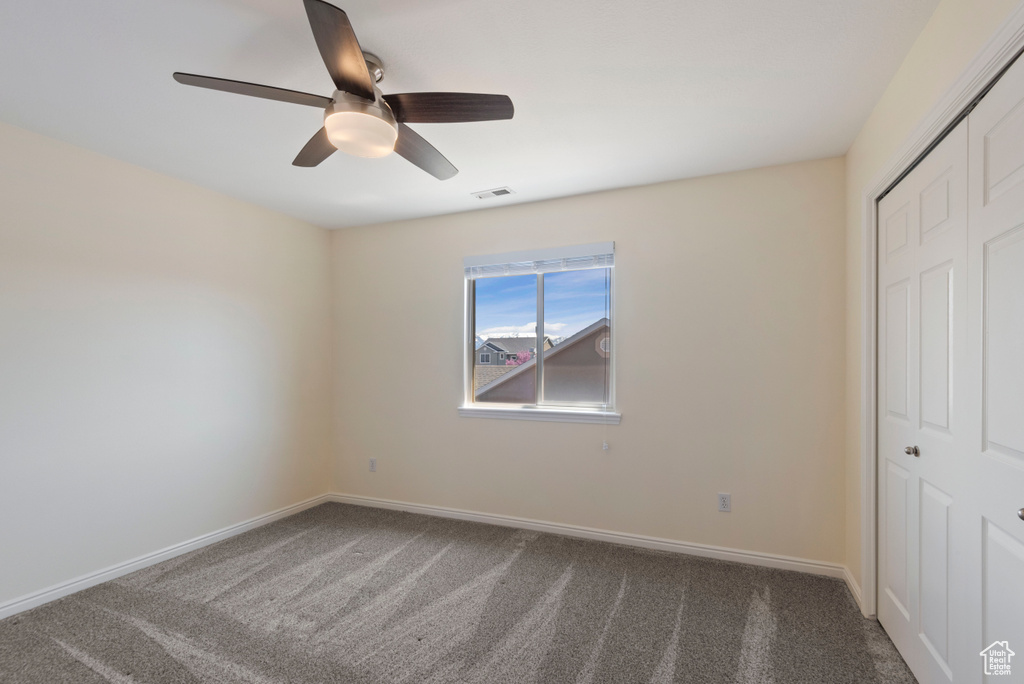 Unfurnished bedroom with dark colored carpet, a closet, and ceiling fan
