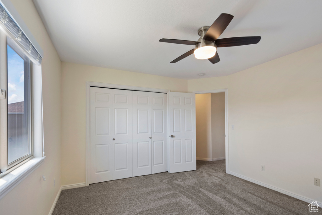 Unfurnished bedroom with a closet, light carpet, ceiling fan, and multiple windows