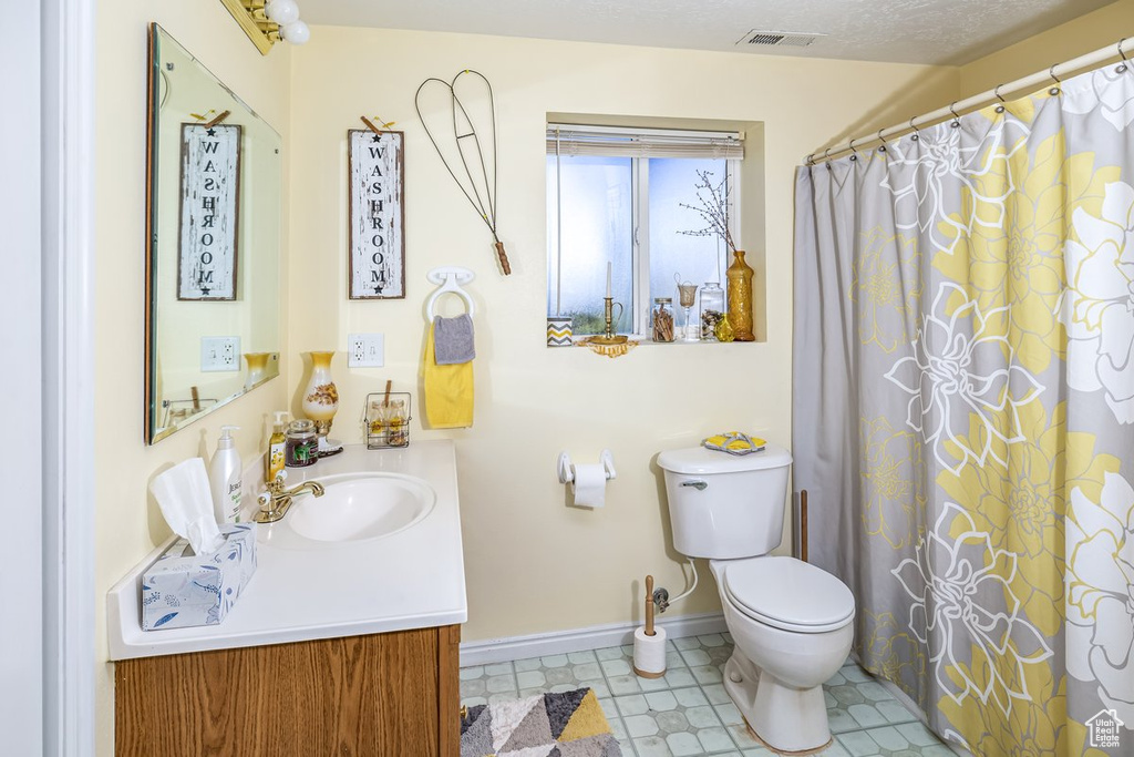 Bathroom featuring a textured ceiling, large vanity, tile floors, and toilet