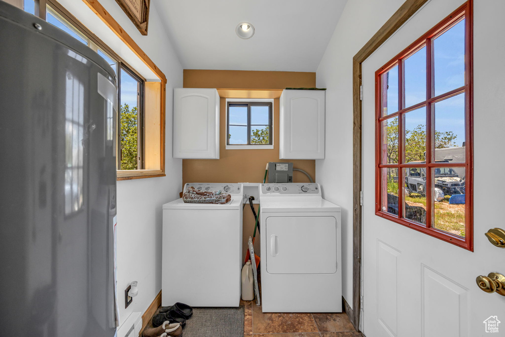 Laundry room featuring light tile flooring, cabinets, and washer and dryer