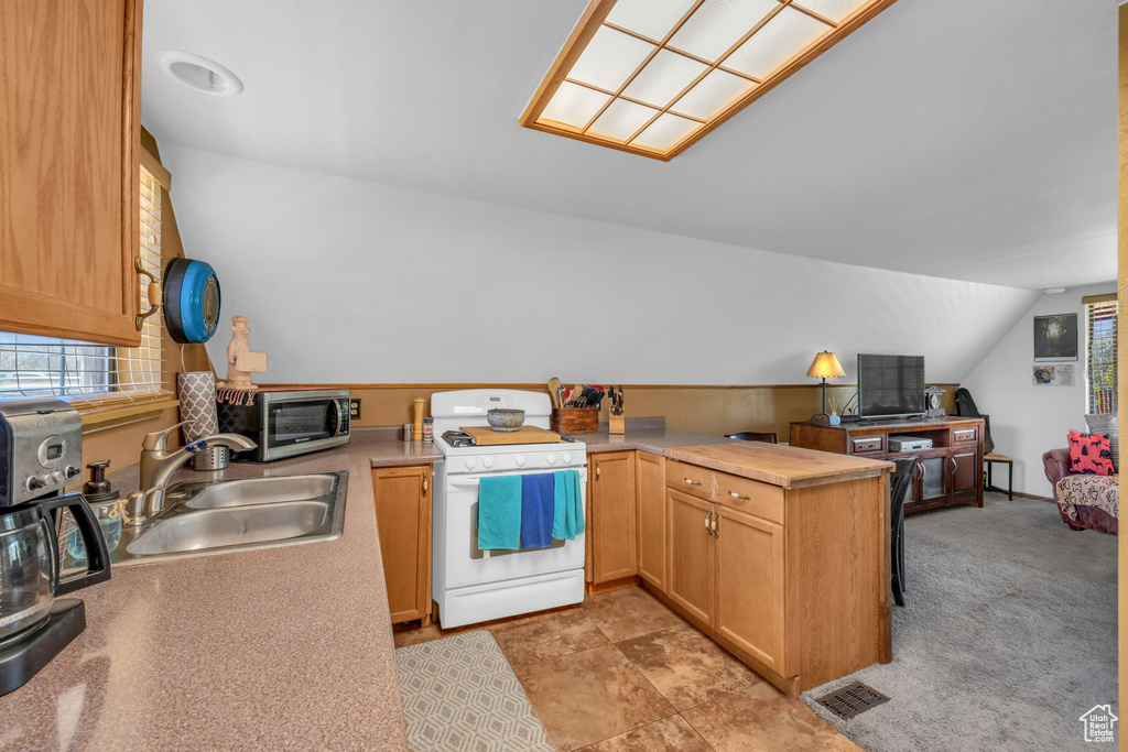 Kitchen with light carpet, white gas range, vaulted ceiling, and sink