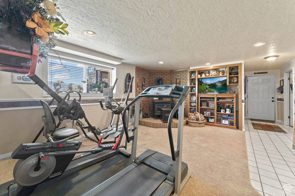 Exercise room with light tile flooring and a textured ceiling