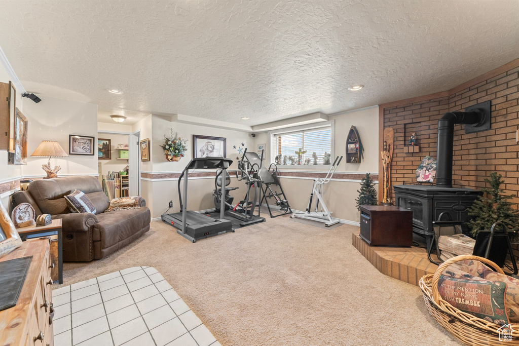 Exercise room featuring a wood stove, light colored carpet, and a textured ceiling