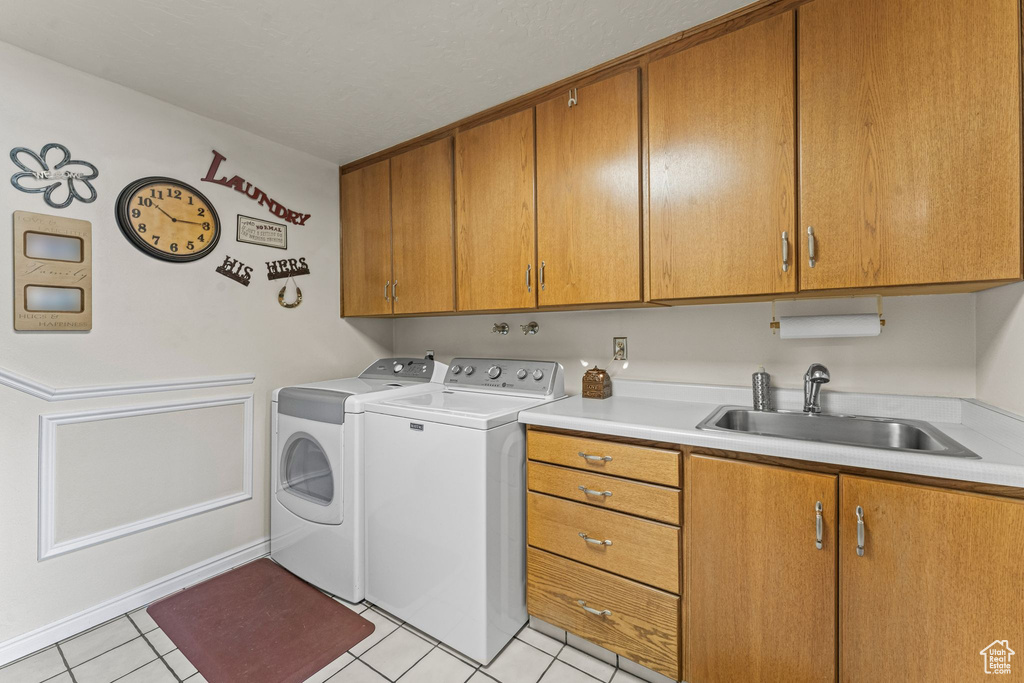 Washroom featuring cabinets, light tile floors, sink, and washer and dryer