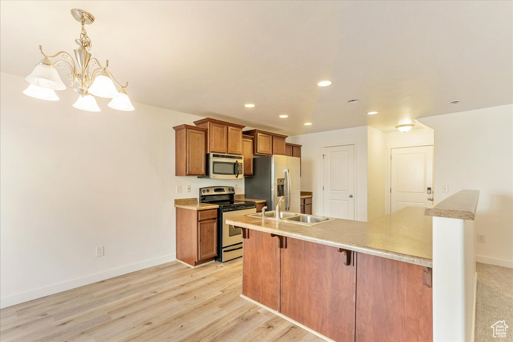 Kitchen featuring pendant lighting, light hardwood / wood-style flooring, appliances with stainless steel finishes, sink, and a kitchen bar