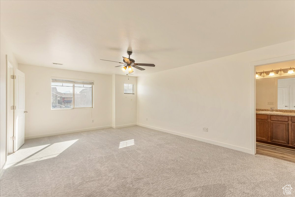 Unfurnished room featuring light colored carpet, sink, and ceiling fan