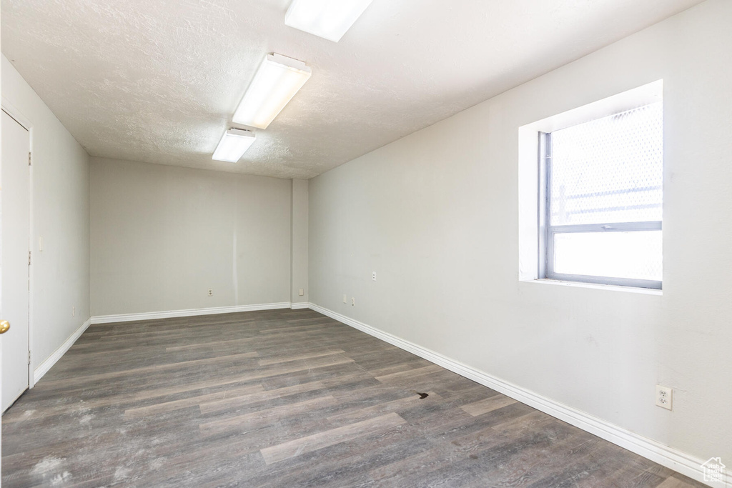 Unfurnished room with a textured ceiling and dark wood-type flooring