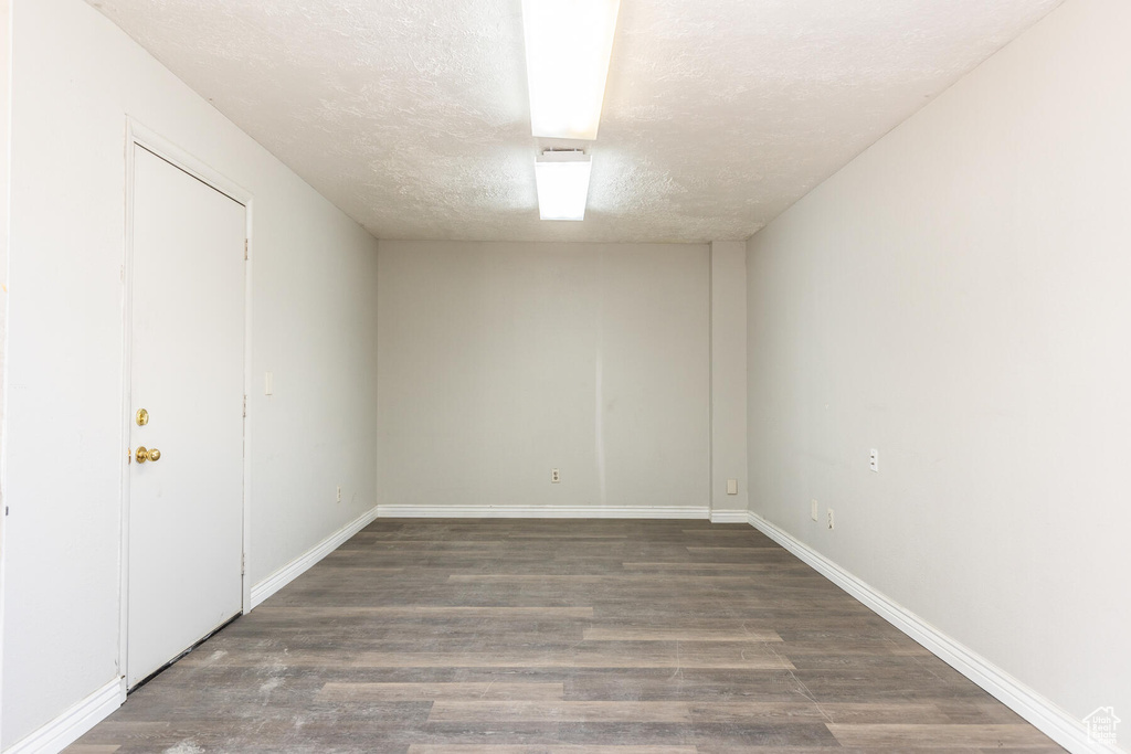 Unfurnished room featuring dark hardwood / wood-style floors and a textured ceiling