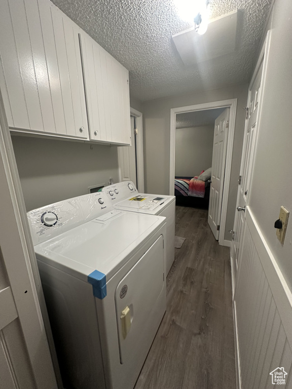 Clothes washing area featuring washer and dryer, cabinets, dark hardwood / wood-style floors, and a textured ceiling