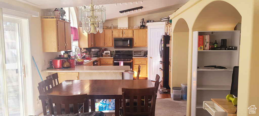 Kitchen with pendant lighting, range, stainless steel refrigerator, carpet flooring, and kitchen peninsula