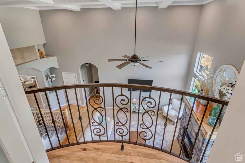 Stairs featuring ceiling fan, a towering ceiling, coffered ceiling, beam ceiling, and light hardwood / wood-style flooring