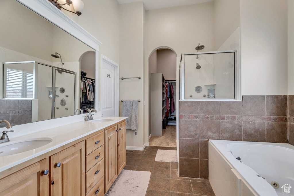 Bathroom with dual bowl vanity, shower with separate bathtub, tile flooring, and a high ceiling