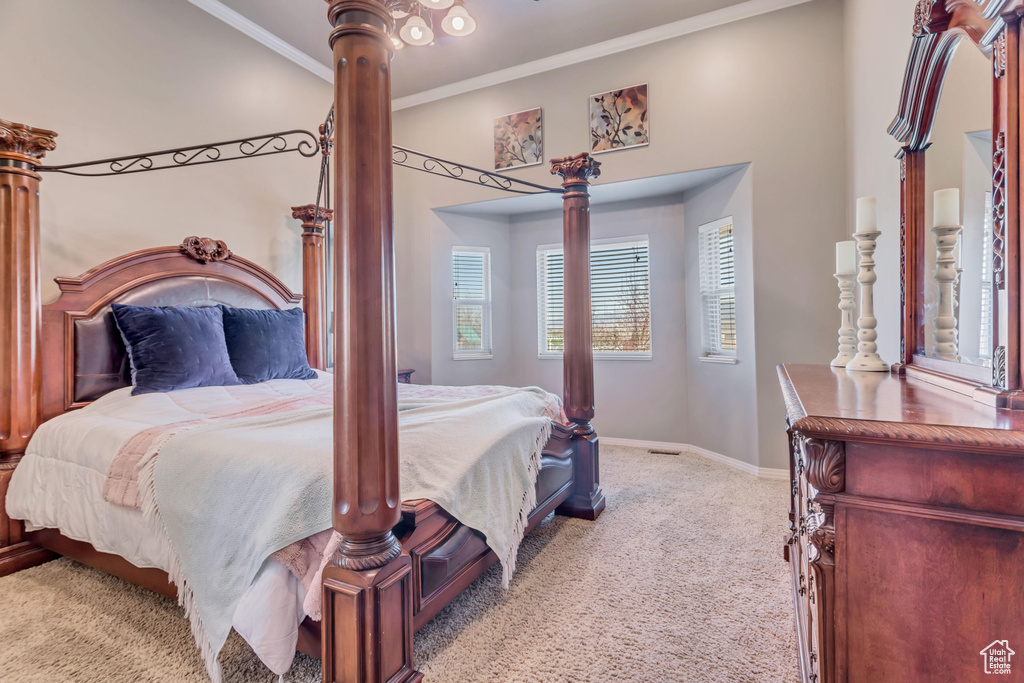 Carpeted bedroom featuring ornate columns and crown molding