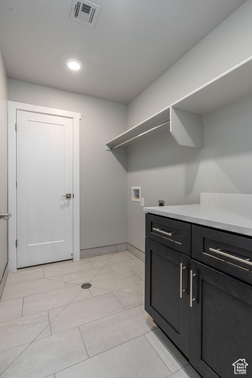 Clothes washing area with washer hookup, electric dryer hookup, cabinets, and light tile flooring