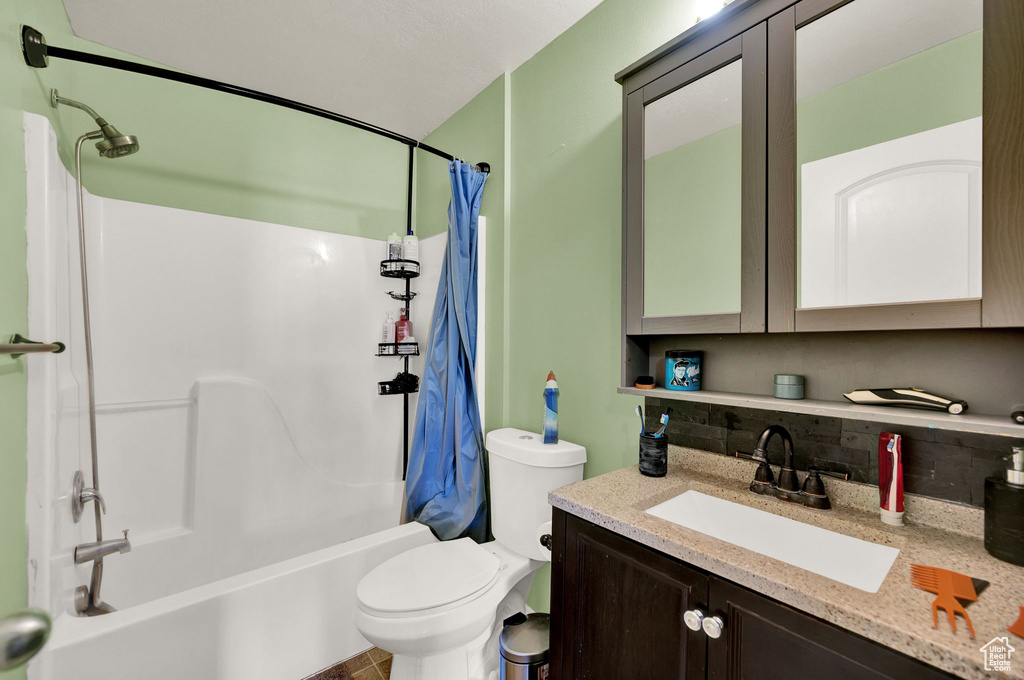 Full bathroom with shower / bath combo with shower curtain, tile floors, vanity, backsplash, and toilet