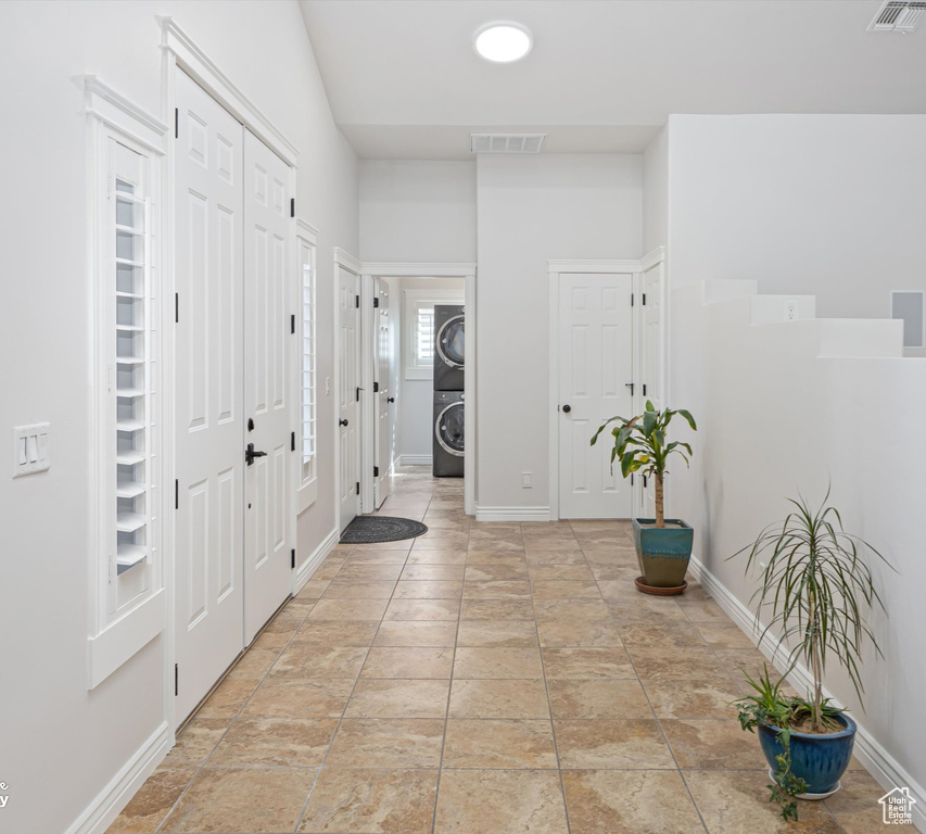 Foyer entrance featuring light tile floors and stacked washer / drying machine