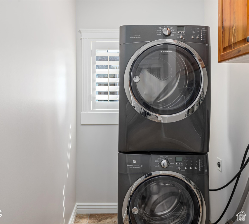 Laundry room featuring cabinets and stacked washing maching and dryer