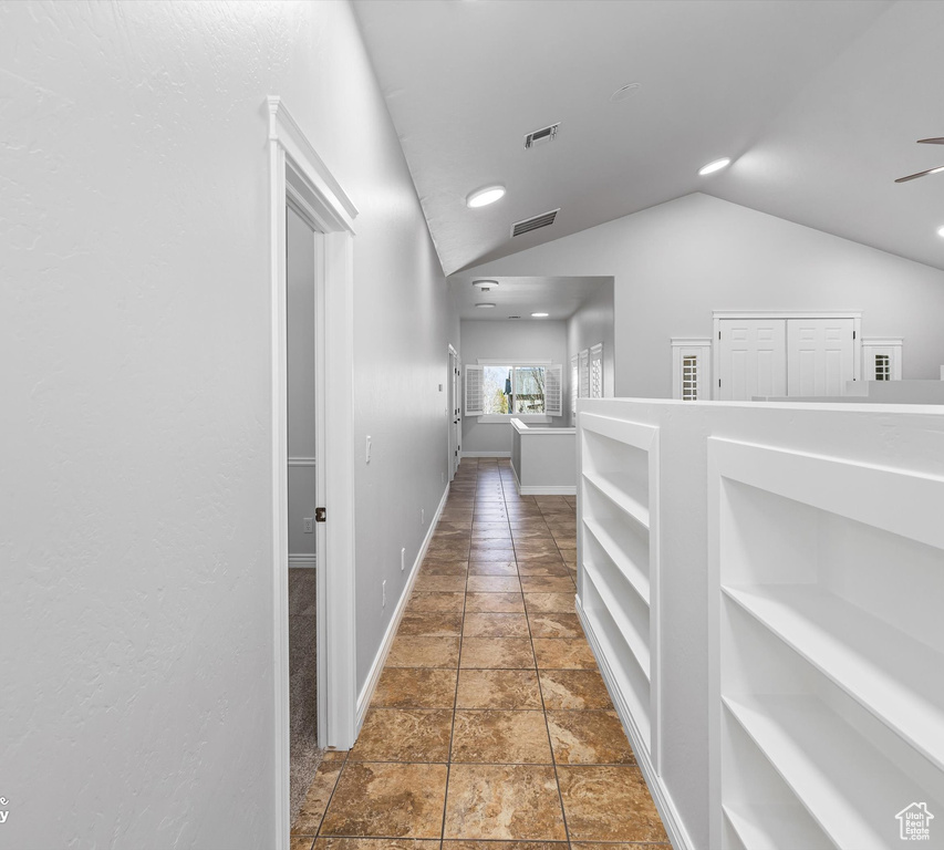 Corridor with lofted ceiling and dark tile flooring