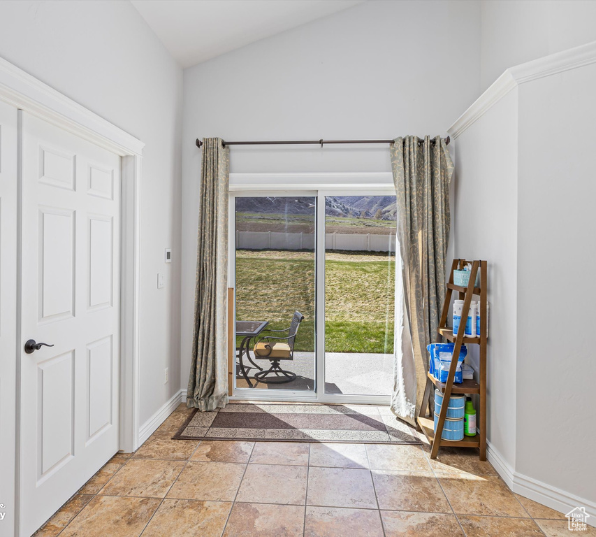 Doorway to outside with vaulted ceiling and light tile floors